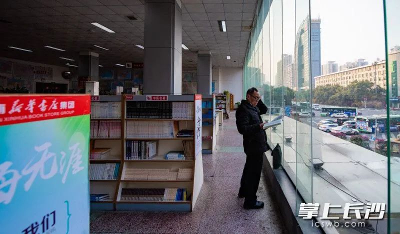 一位老先生正站在玻璃窗前看書圖片